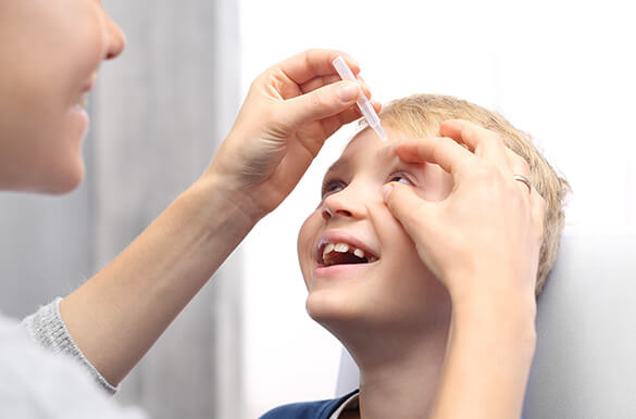 Image of adult administering drops into childs eye for atropine drops